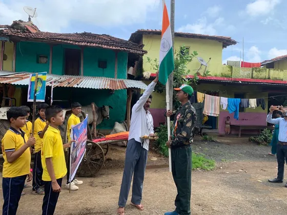 Students in yellow T-shirts stand at attention as the national flag is hoisted in the village.